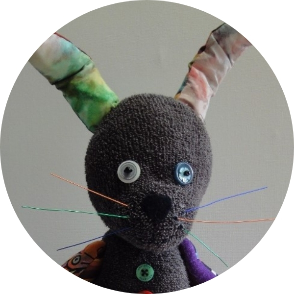 Close up of Thackery Earwicket, a hand sewn sock rabbit with button eyes and tie dyed ears