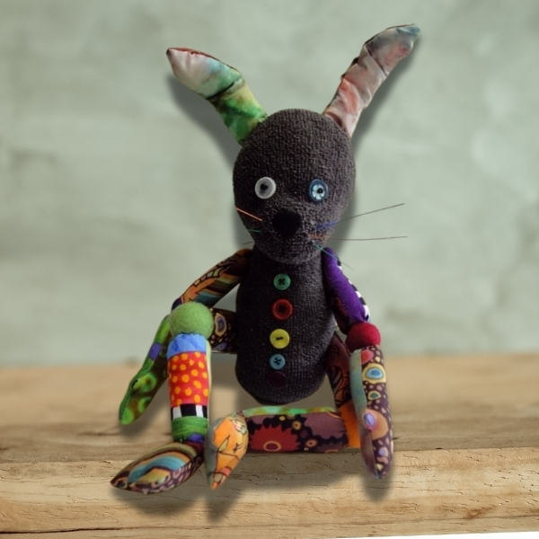Thackery Earwicket, a handmade sock rabbit doll with patchwork limbs and embroidered whiskers
