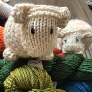 2 knitted sheep climbing a pile of yarn