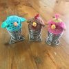 Three bird shaped egg cosies on eggs.